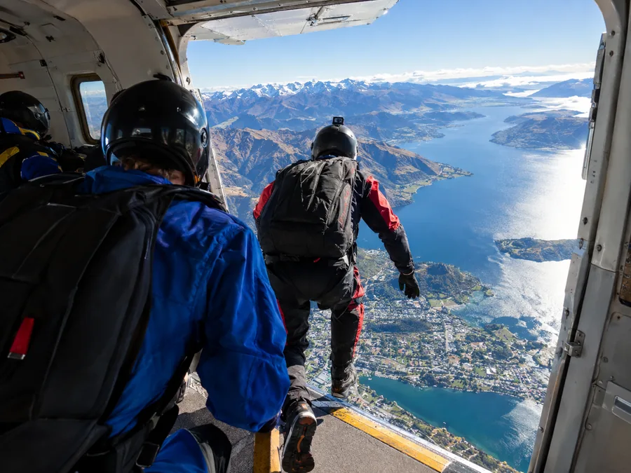 Un sauteur à la porte ouverte d'un avion de parachutisme au-dessus du lac Wakatipu